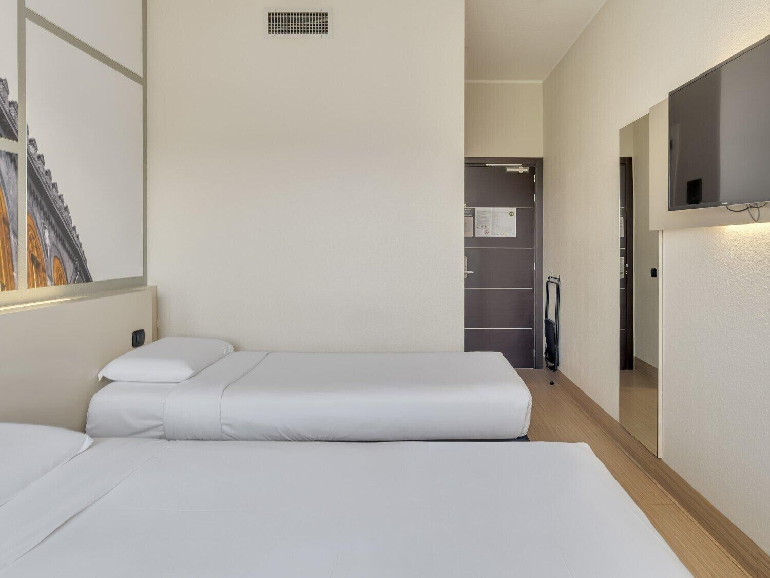 A hotel room with two beds, a large mirror, and a door leading to a bathroom.