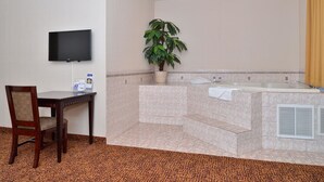 Une salle de bain d’hôtel équipée d’une baignoire, d’un lavabo, d’une douche, d’un téléviseur fixé au mur et d’une chaise.