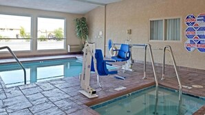 Une piscine intérieure à l’eau claire, avec un poste de surveillance pour le sauveteur et un panneau indiquant qu’il est interdit de plonger, fixé au mur.