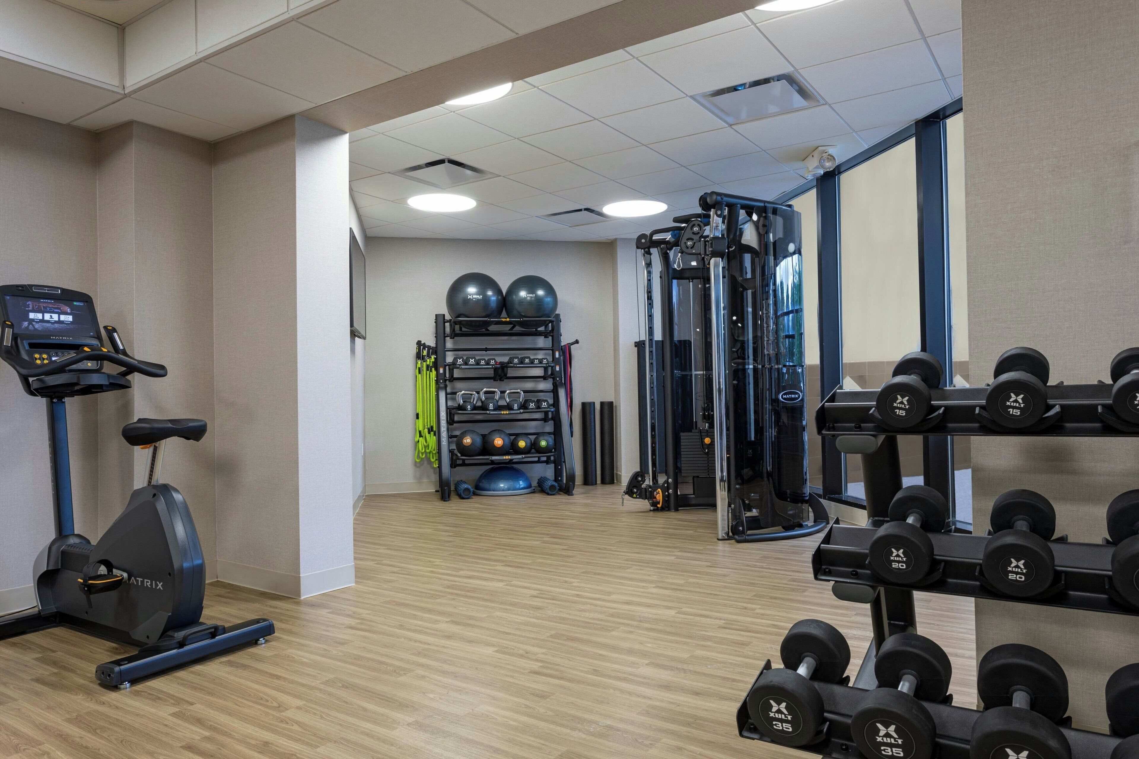 A gym with cardio equipment, weightlifting stations, and exercise balls.