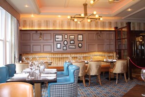 A formal dining area with a long table, blue and brown upholstered chairs, and a patterned floor. - The Abbey Hotel Donegal (Donegal)