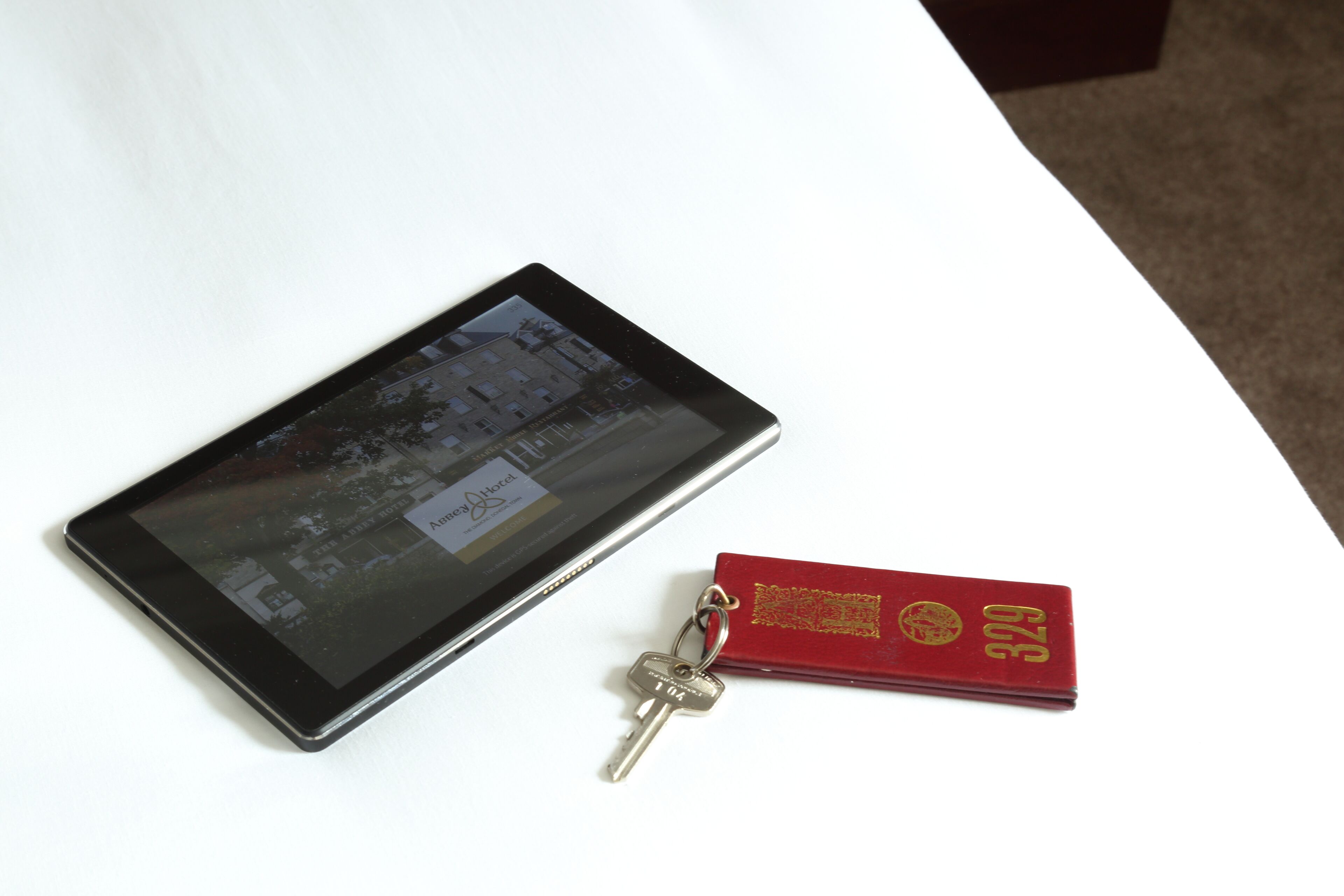A tablet and a red keychain with a hotel logo on a white surface.