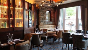A restaurant with a stone wall, wooden furniture, and a patterned floor. - The Abbey Hotel Donegal (Donegal)