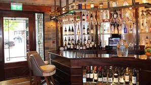 A bar area with a variety of bottles and glasses on shelves, a bar counter, and two bar stools. - The Abbey Hotel Donegal (Donegal)