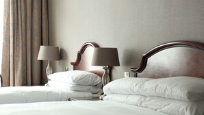 A hotel room with two beds, each with white linens and pillows, a wooden headboard, and two bedside lamps. - The Abbey Hotel Donegal (Donegal)