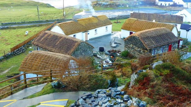 A traditional village with stone houses, a thatched-roof building, and a river in the background. - The Abbey Hotel Donegal (Donegal)