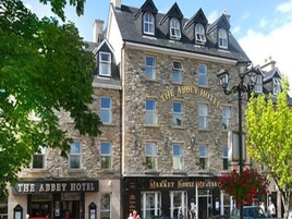 El Hotel Abbey con fachada de piedra, múltiples ventanas y un letrero que anuncia el Restaurante Market House.