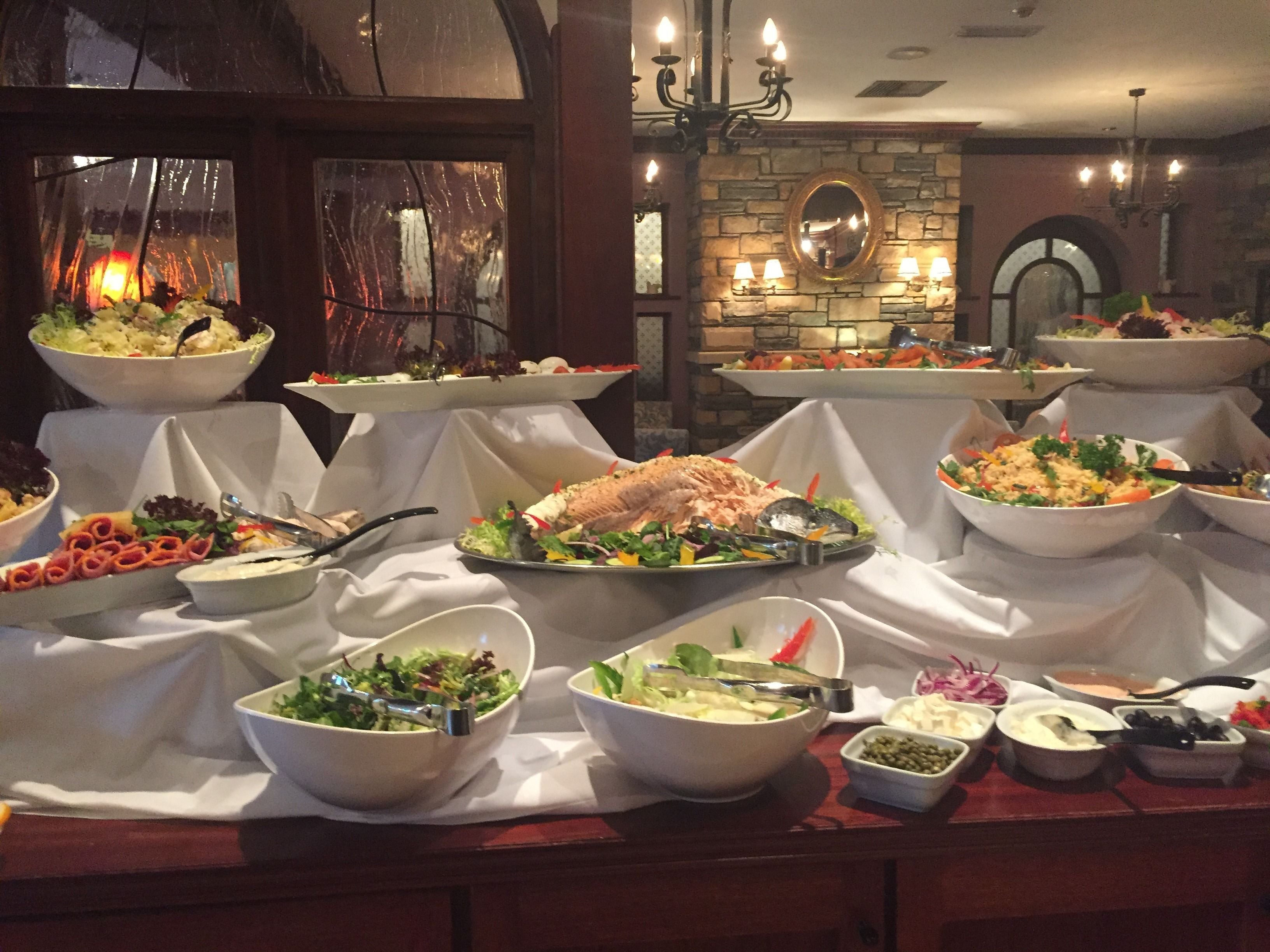 A buffet setup with various dishes and a stone wall backdrop.
