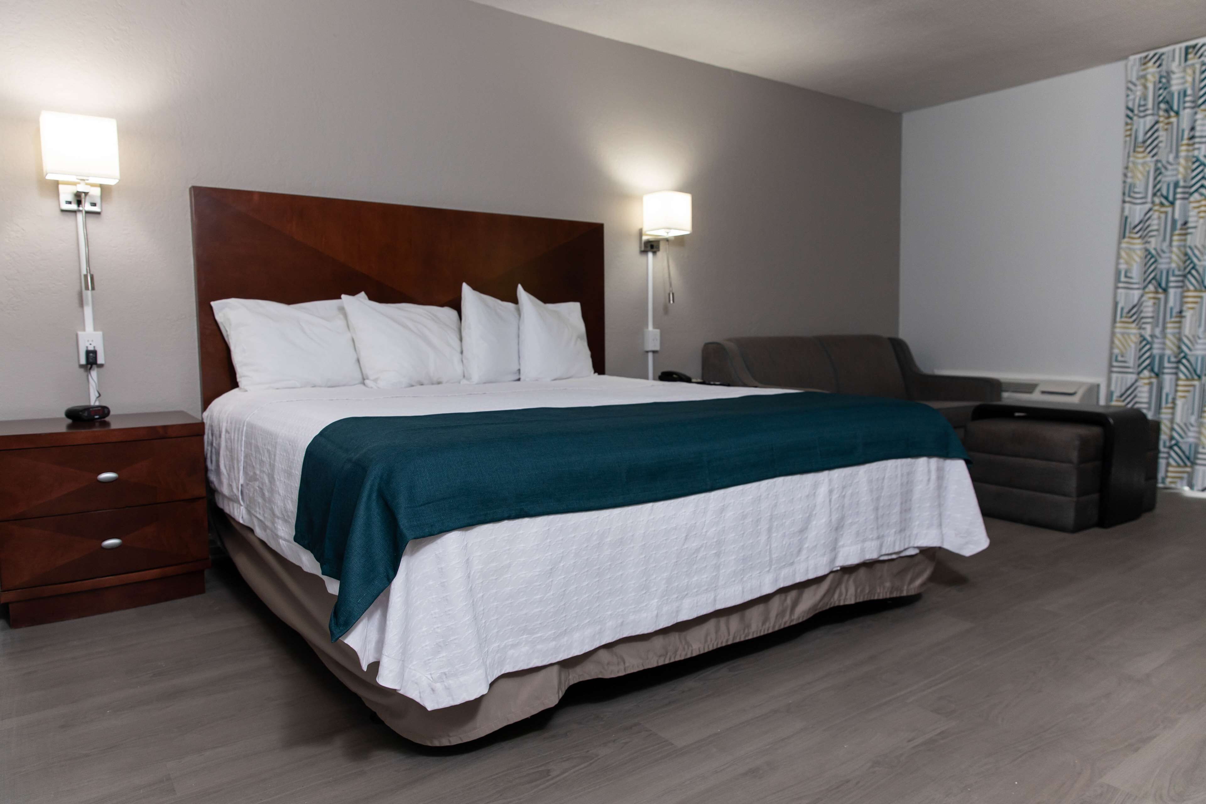 Una habitación de hotel con una cama grande, lámparas de noche, un escritorio y una silla.