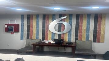A reception area with a large number '6' on the wall, a fire alarm, and a desk with a computer and chair.