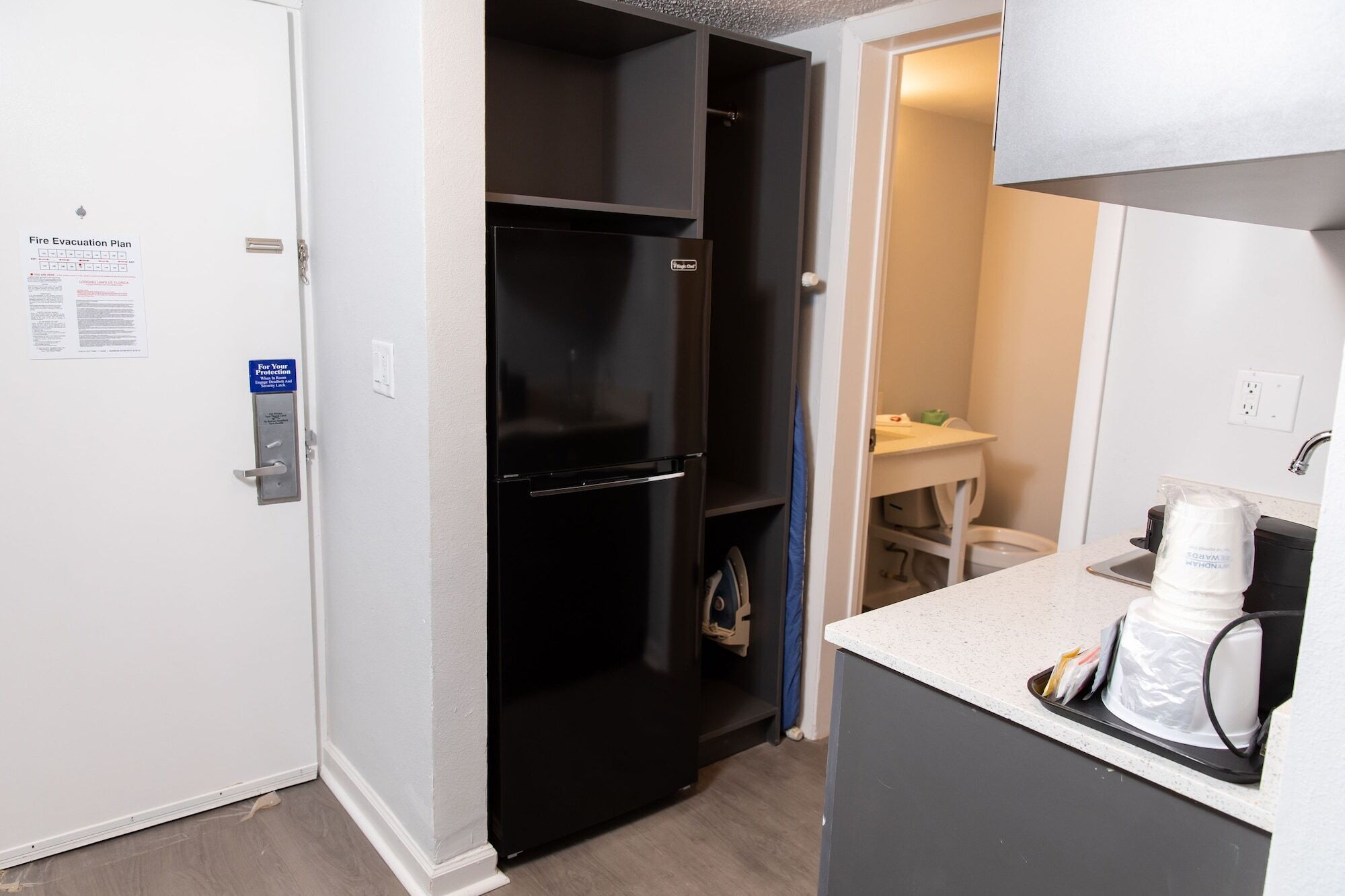 A compact kitchen with a black refrigerator, a small table, and a coffee maker on the countertop.