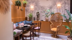 Una habitación acogedora con un sofá, sillas, una mesita y plantas colgantes.