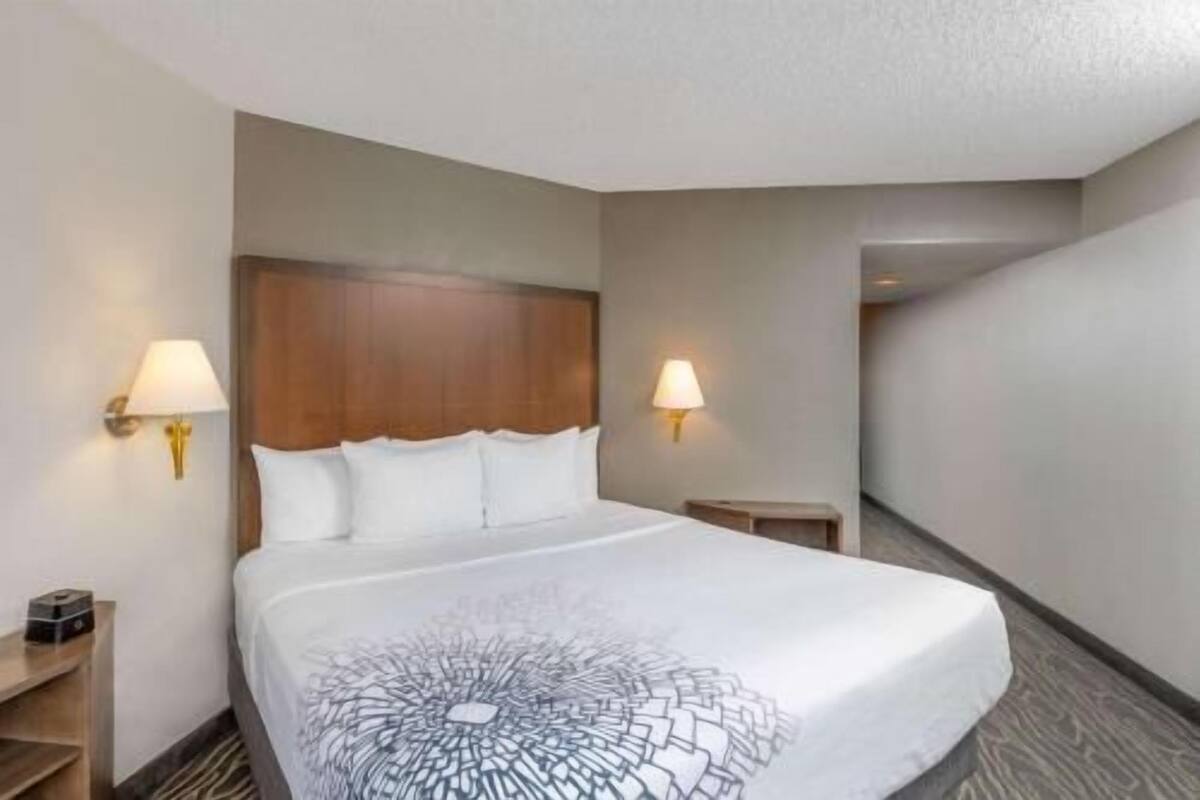 Ein Hotelzimmer mit einem großen Bett, zwei Nachttischlampen, einem Holzkopfende und einem kleinen Nachttisch.