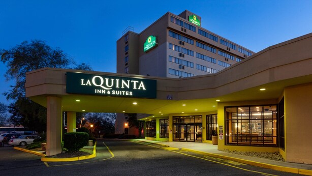 Exterior de La Quinta Inn & Suites, con entrada despejada, estacionamiento y un edificio de varios pisos.