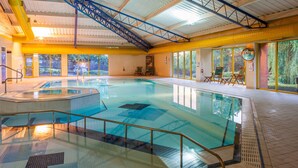 An indoor swimming pool with a hot tub, clear glass railings, and a view of the outdoors through large windows. - Holiday Inn Runcorn by IHG (Runcorn)