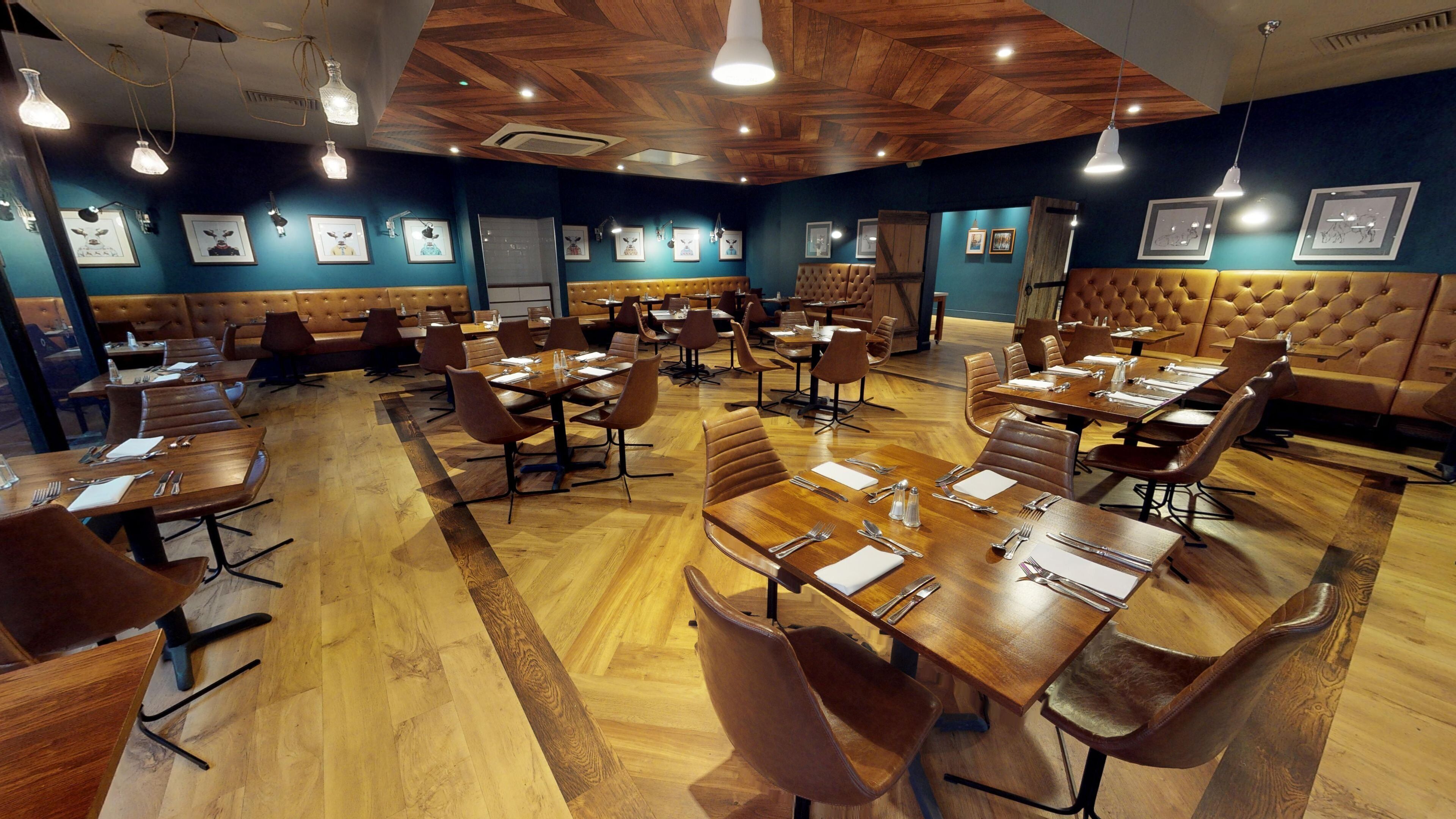 A restaurant with wooden tables and booths, framed pictures on the walls, and a wooden ceiling.