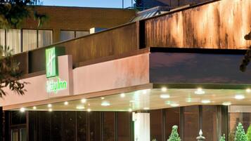 Un hotel Holiday Inn con fachada de ladrillo, un acceso cubierto y una escalera que lleva al edificio principal.