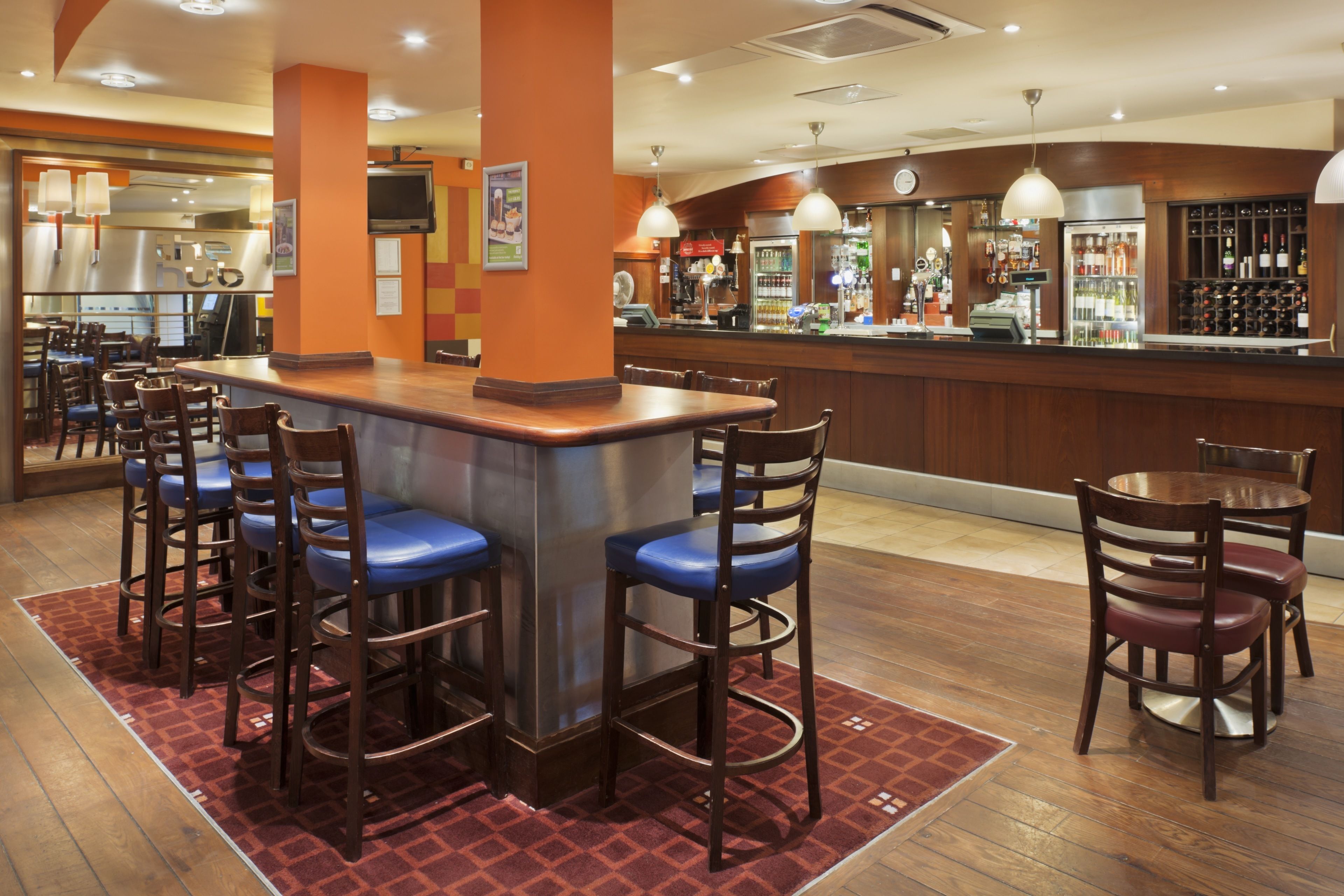 A bar area with stools, a counter, and a bar stocked with bottles.