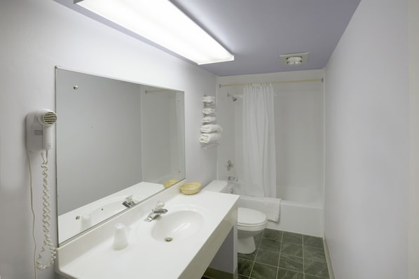 A bathroom with a white sink, mirror, and toilet. There is a shower curtain and a towel rack with towels.