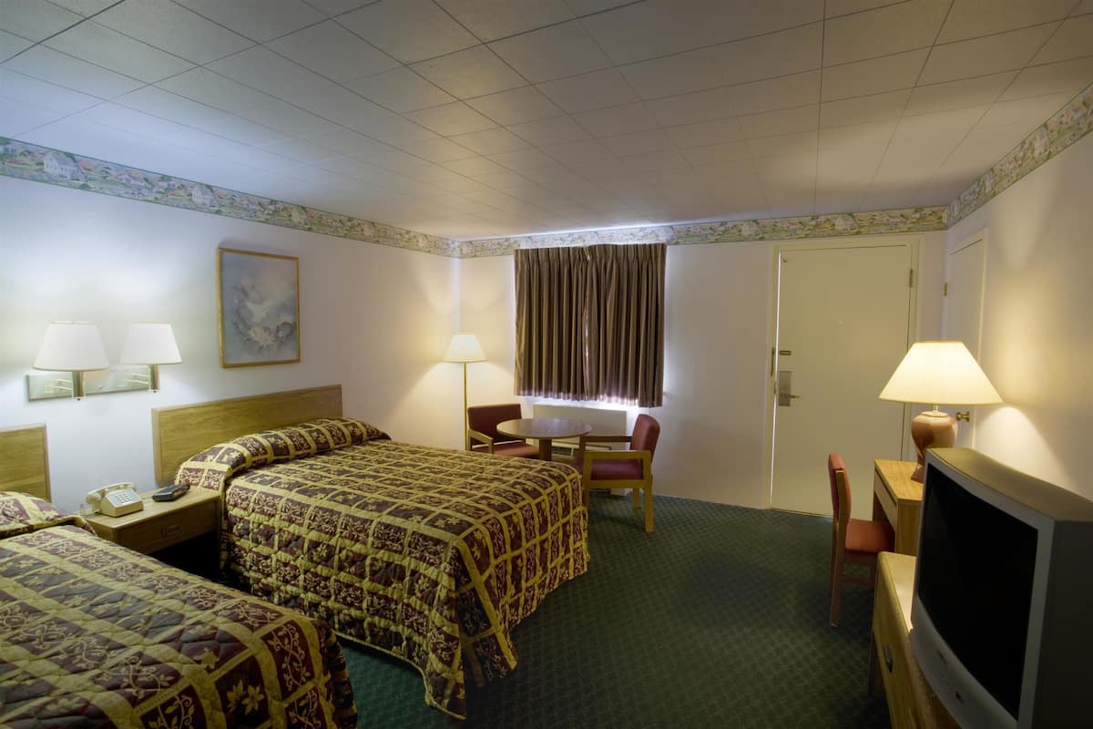 A hotel room with a large bed, two bedside tables with lamps, a television, and a desk with a chair.