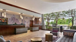En moderne lobby med reception, siddeområde og store vinduer med udsigt over et grønt landskab.