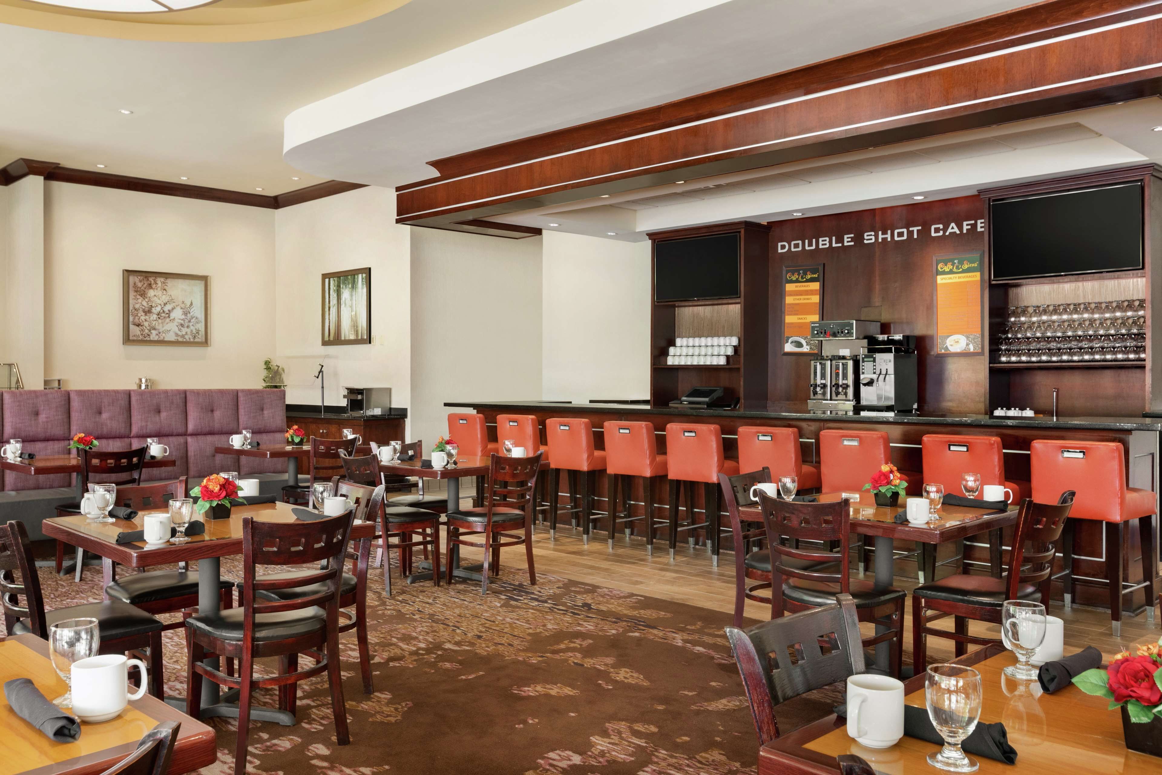 A hotel lobby with a bar area, seating arrangements, and a coffee station.