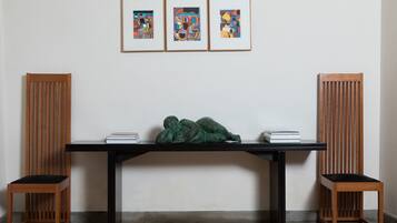 Ein Zimmer mit einem schwarzen Tisch, zwei Holzstühlen und drei gerahmten abstrakten Bildern an der Wand.