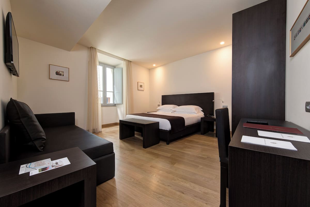 Une chambre d’hôtel moderne équipée d’un lit, d’un canapé, d’un bureau et d’une télévision.