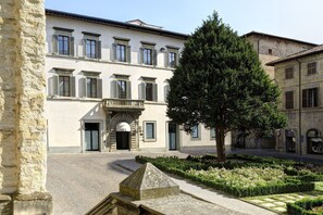 A historic building with a central entrance, a courtyard with a tree, and a stone monument. - Hotel Tiferno (Città di Castello)