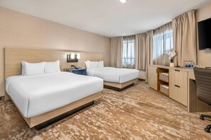 A hotel room with two beds, a desk, a TV, and a window with curtains. - Comfort Inn Montreal - Laval - Highway 15 (Laval)
