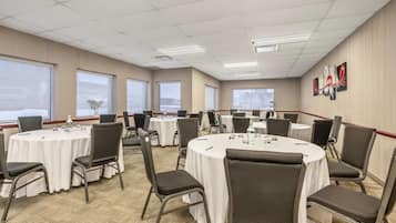 Un salón de conferencias con mesas redondas, sillas y manteles blancos.