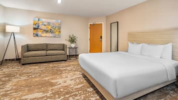 Une chambre d’hôtel avec un grand lit, un canapé, une petite table avec une plante et un tableau au mur.
