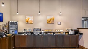A breakfast bar with a refrigerator, coffee machine, and various food items.