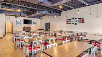 A spacious dining area with multiple tables and chairs, a flat-screen TV mounted on the wall, and a fireplace.