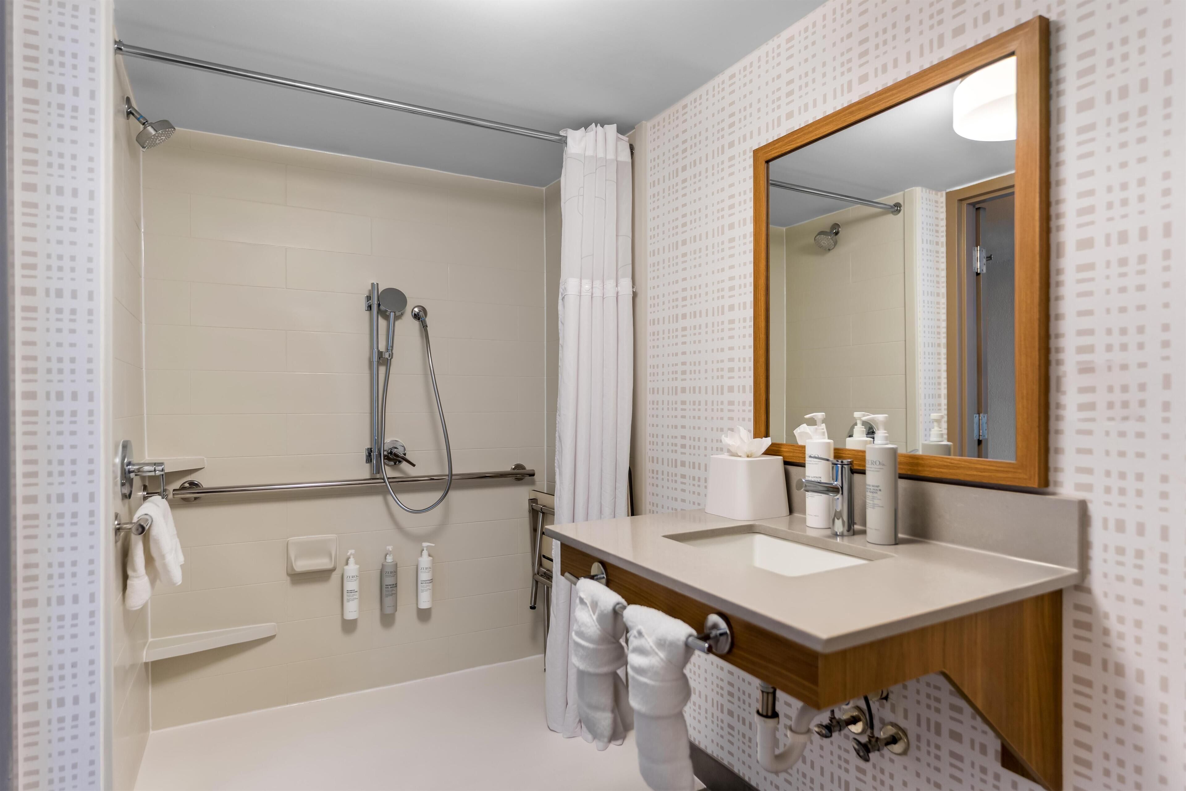 Un baño moderno con ducha, lavamanos y espejo.