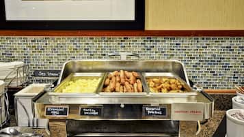 A buffet with labeled containers of scrambled eggs, turkey sausage, and seasoned potatoes.