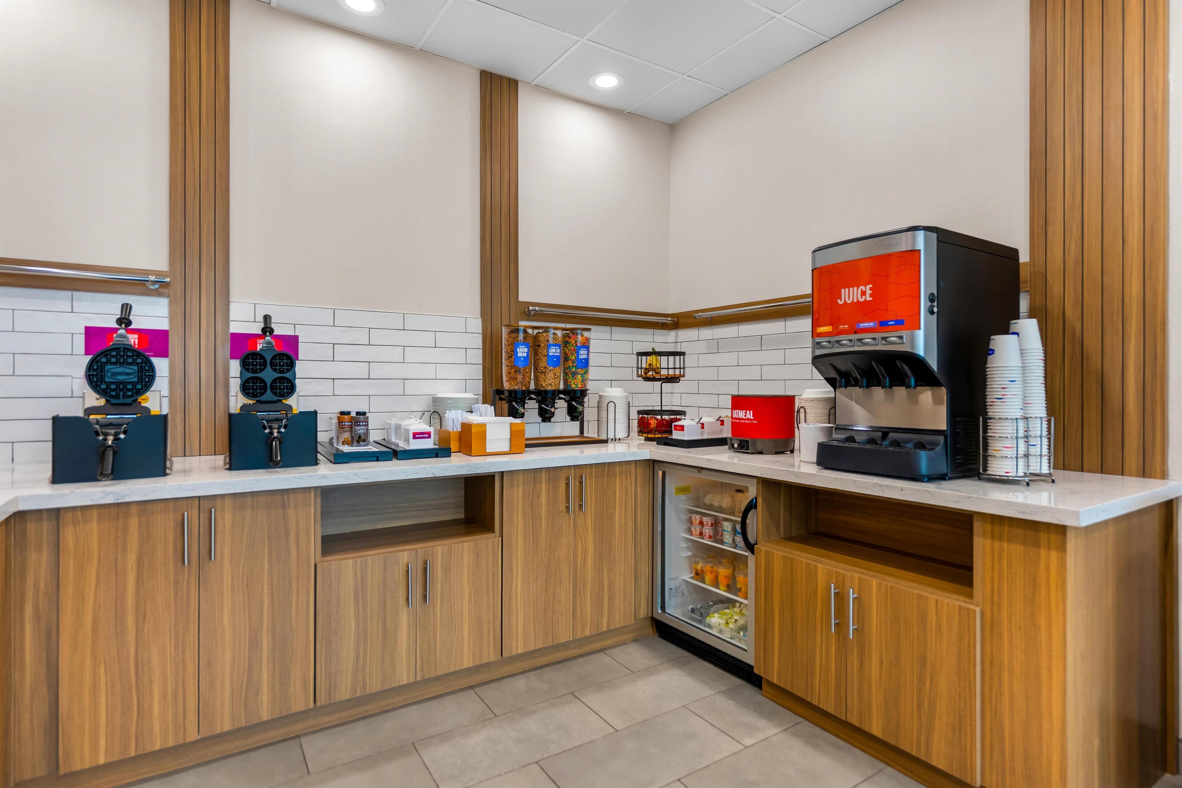 A modern kitchen with a coffee machine, condiment dispensers, and a refrigerated section.