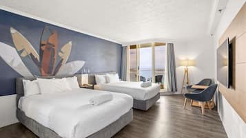 A hotel room with two beds, a desk, a chair, a TV, and a large window with a view.