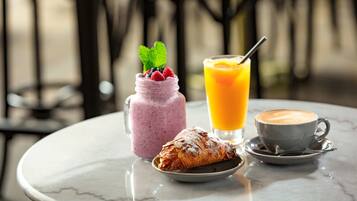A table with a dessert, a smoothie, a glass of orange juice, and a cup of coffee.