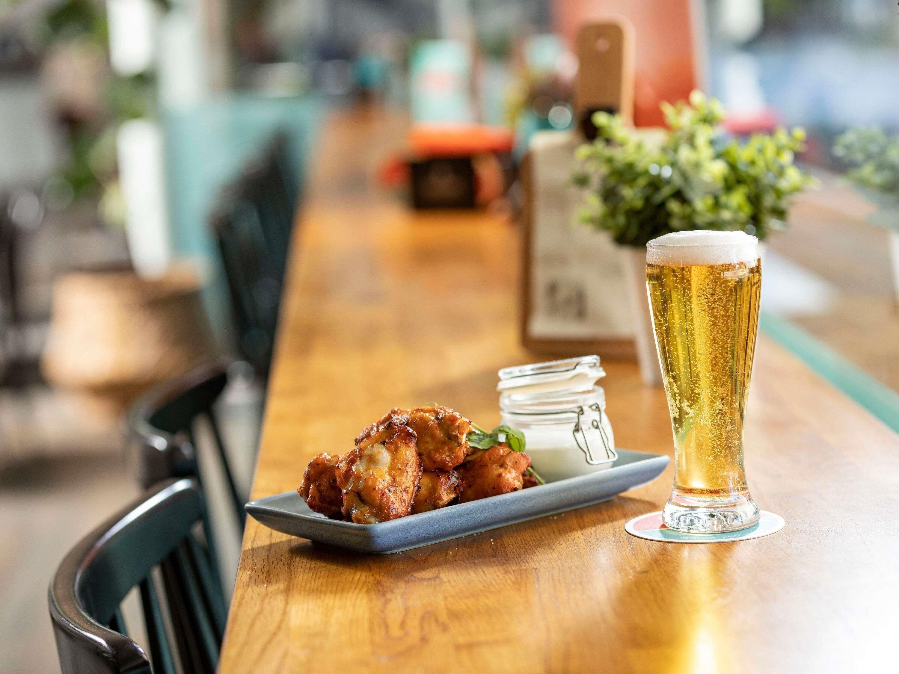 Una barra de madera con un plato de comida y una jarra de cerveza.