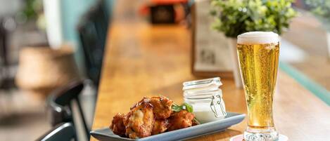 A wooden bar with a plate of food and a glass of beer.