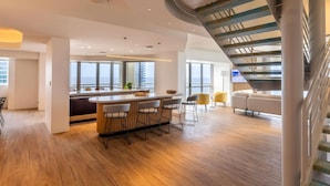 A modern interior with a central bar, seating area, and a spiral staircase. - Novotel Surfers Paradise (Surfers Paradise)