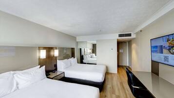 A hotel room with two beds, a desk, a chair, a TV, and a mirror.