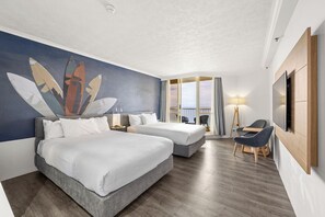 A hotel room with two beds, a TV, a desk, and a chair.