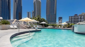 A swimming pool with lounge chairs and umbrellas, surrounded by high-rise buildings. - Novotel Surfers Paradise (Surfers Paradise)