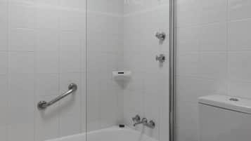 Ein modernes Badezimmer mit einer Duschkabine aus Glas, einer weißen Badewanne und einem WC.