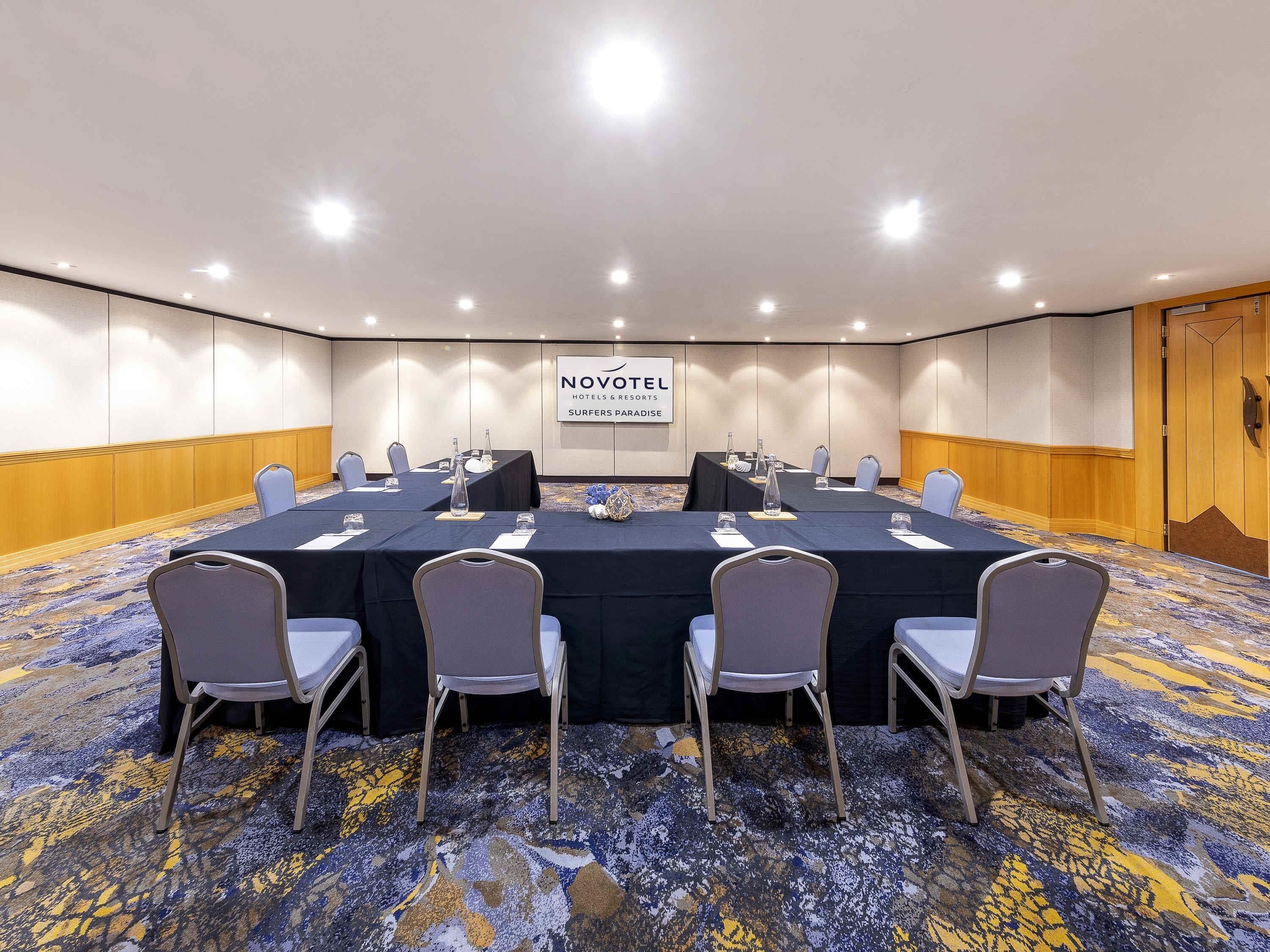 A conference room with a long table, chairs, and a carpeted floor.