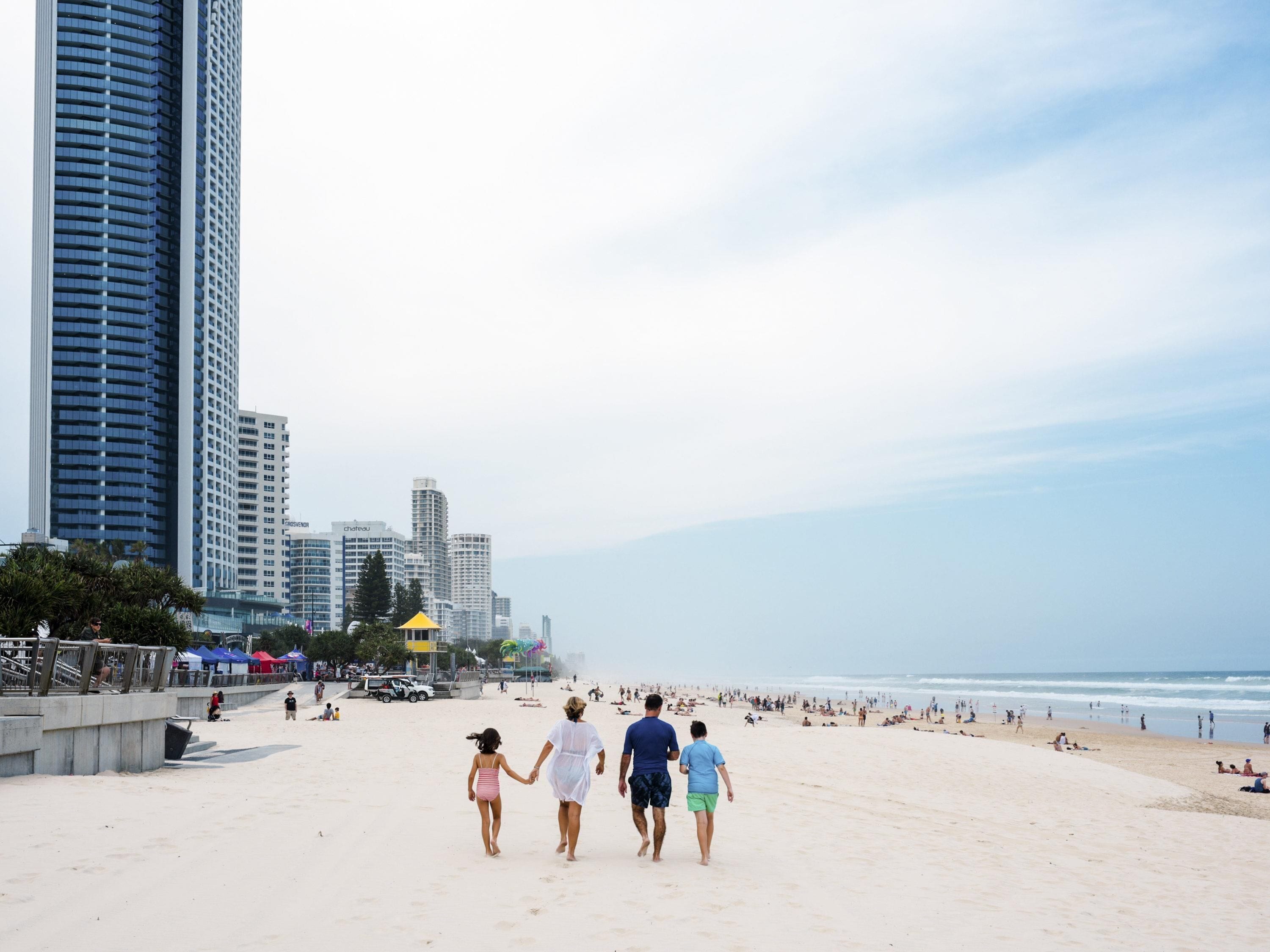 Een strand met wandelaars, een stadsachtergrond en een zandstrand.