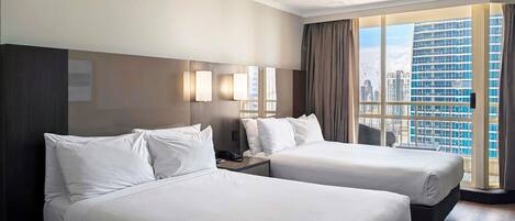 A hotel room with two beds, a city view, and a modern design.