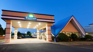 A Days Inn hotel entrance with a clear sky, a gas station sign, and a parking lot. - Days Inn by Wyndham Norman (Norman)